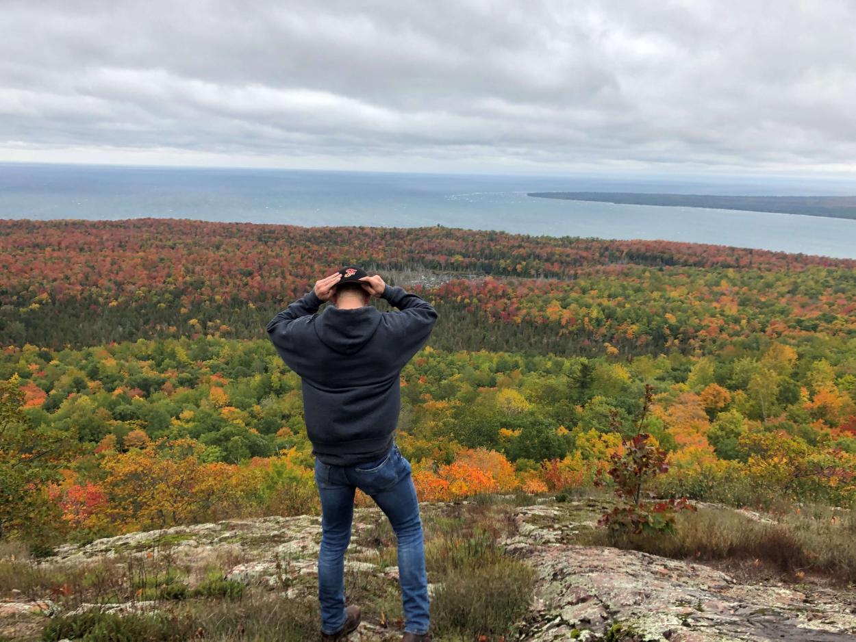 Student standing atop mountain looking at fall colors.